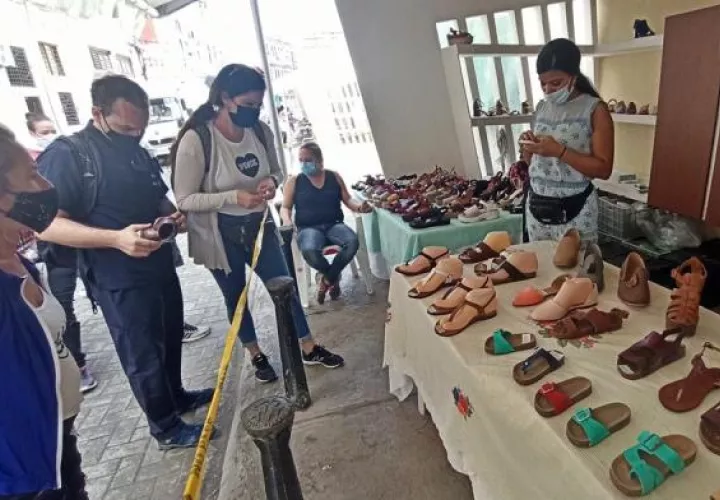 Varias personas observan algunos modelos en un puesto de venta de sandalias hoy, en La Habana