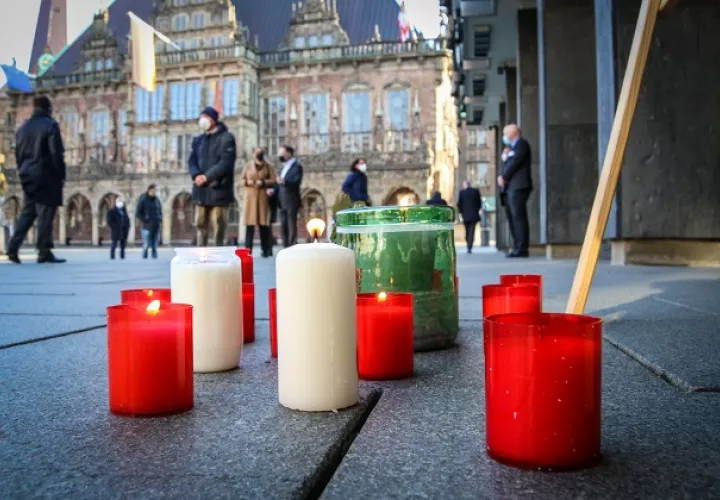  Velas encendidas reposan sobre el pavimento durante una ceremonia para conmemorar las muertes de coronavirus frente al parlamento estatal de Bremen. Foto: EFE