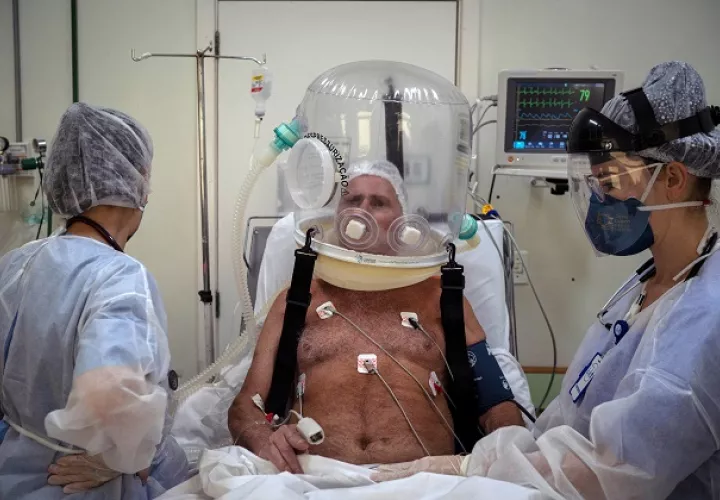 Trabajadores de la salud atienden con un casco burbuja a un paciente con la covid-19 en Brasil. Foto: EFE