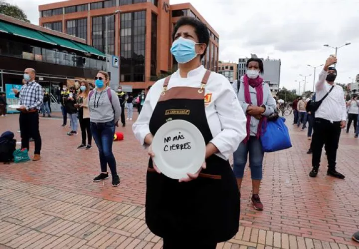 Una mujer sostiene un plato durante una protesta del gremio Asobares, hoy en Bogotá (Colombia).