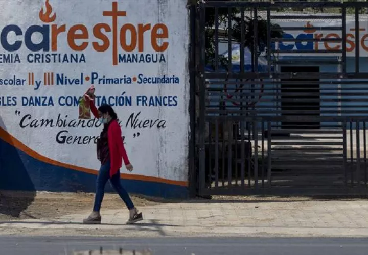 Un mujer camina frente a la puerta cerrada de una escuela hoy en Managua (Nicaragua). Foto: EFE