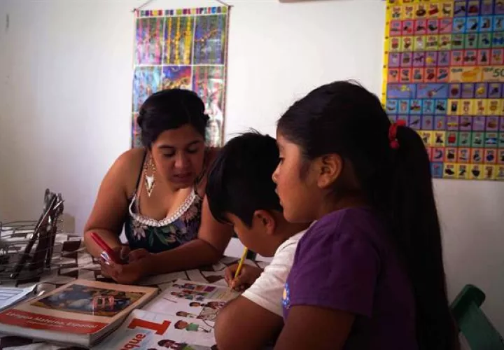 Una mujer acompaña a sus hijos en sus tareas.