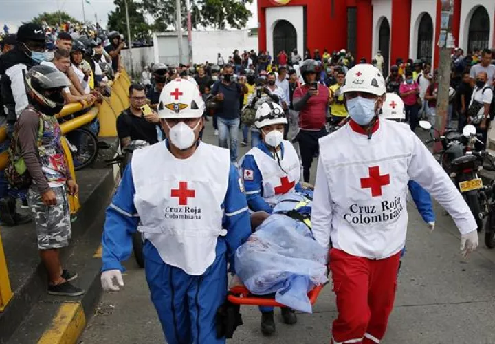 Miembros de la Cruz Roja Colombiana levantan el cuerpo sin vida de un hombre hoy, durante las manifestaciones en el sector La Luna, en Cali (Colombia).