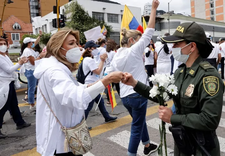 Una mujer y una policía se saludan hoy en Bogotá, Colombia, durante una marcha que rechaza y pide el fin del "Paro Nacional" y la violencia. Foto: EFE