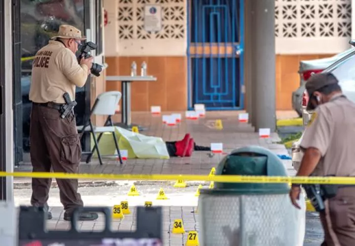 Un oficial de policía fotografía el cuerpo de una de las víctimas del tiroteo registrado en la entrada del salón de banquetes Billiards en Miami Gardens, Florida, Estados Unidos, este 30 de mayo. 