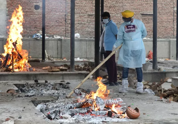 Voluntarios desinfectan durante un funeral masivo de víctimas de covid-19 en un crematorio en Nueva Delhi, India. Foto: EFE