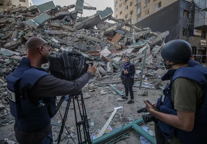 El equipo de televisión palestino trabaja junto a los escombros de su oficina destruida, la torre Al-Jalaa, que alberga apartamentos y varios medios de comunicación en la ciudad de Gaza. Foto: EFE