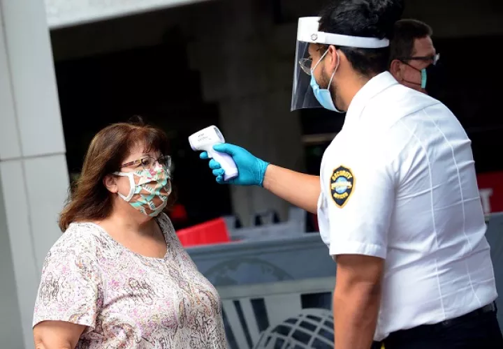 Un agente de seguridad de Universal Studios mide la temperatura a una señora que ingresa a dicho parque temático en Orlando, Florida (EE.UU).
