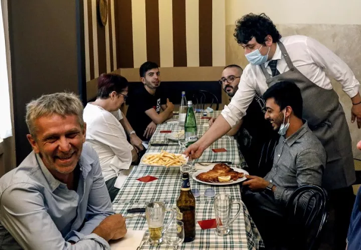 Los clientes comen hoy dentro de un restaurante siguiendo las medidas de seguridad después de la reapertura, en Milán, Italia. Foto: EFE 