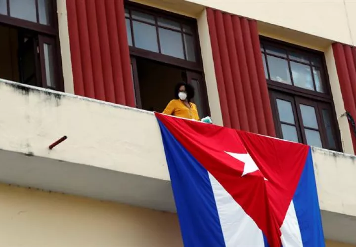 Una mujer sale al balcón donde se expone una bandera cubana, en La Habana, Cuba. EFE