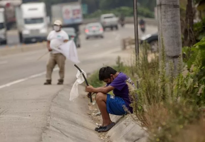 Un niño ondea una bandera blanca en la carretera pidiendo ayuda por hambre debido a la crisis economica provocada por el coronavirus, en Guatemala. EFE