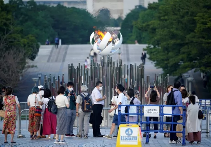 Personas se toman fotos con la Llama Olímpica en Tokio, Japón, que hoy registró nuevo récord de casos diarios de covid-19. Foto: EFE
