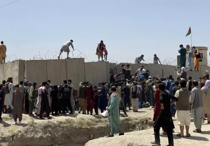 Afganos se agolpan a lo largo del muro del aeropuerto internacional Hamid Karzai antes de saltarlo en un intento de abandonar el país. EFE