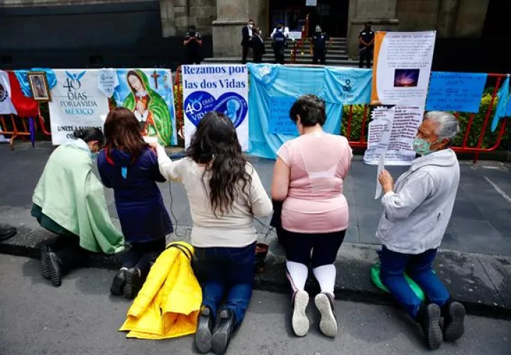 Un grupo de mujeres en contra del aborto rezan frente a carteles de protesta "pro-vida" y religiosos, afuera de la Suprema Corte de Justicia de la Nación, en la Ciudad de México. EFE