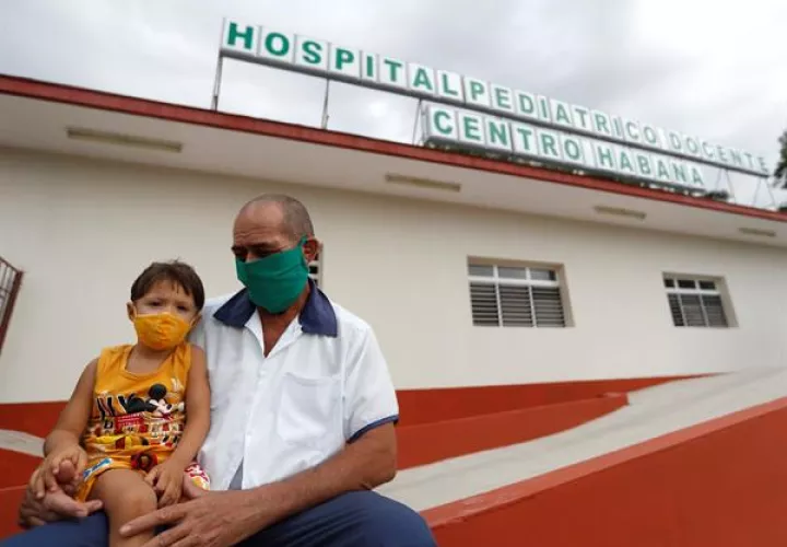 Un trabajador de la salud sostiene a un niño en sus piernas en la entrada de un hospital pediátrico hoy, en La Habana (Cuba). Foto: EFE