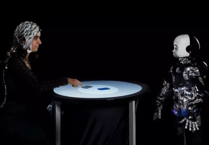 Una persona y un robot humanoide participan en un juego competitivo, mientras se mide su actividad cerebral con un electroencefalograma. Foto: EFE