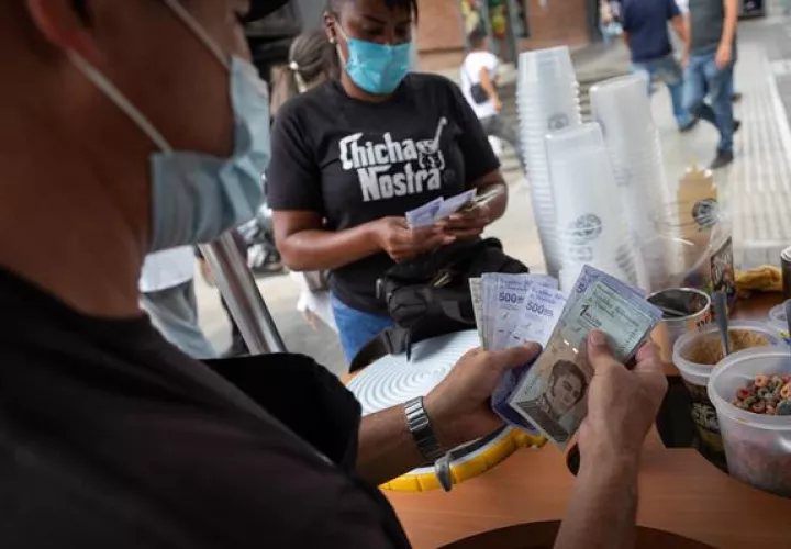 Vendedores cuentan billetes del antiguo cono monetario (Bolívar Soberano). EFE