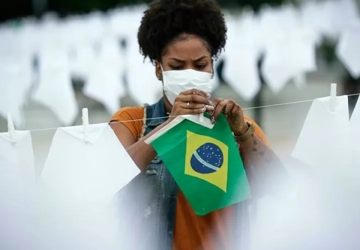 Una voluntaria ayuda a colgar pañuelos blancos durante un homenaje a las miles de víctimas mortales de covid-19 en Río de Janeiro, Brasil, el 8 de octubre de 2021. Foto: EFE