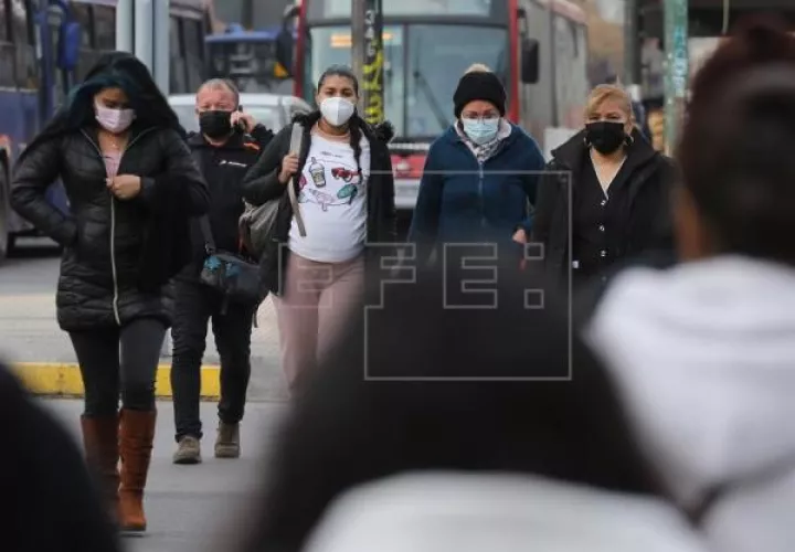 Personas caminan protegidas con mascarillas por una calle en Santiago de Chile. Foto: EFE
