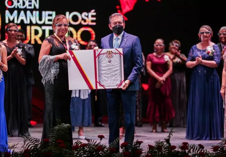 La docente Herminia Gómez Castillo,  representante de la Escuela Oficial Bilingüe Simeón Conte, recibe el pergamino por parte del presidente Laurentino Cortizo. Foto: Cortesía Presidencia