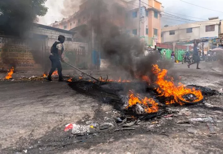 Un policía intenta disipar una barricada en llamas durante una jornada de protesta en Pétion-ville (Haití). EFE