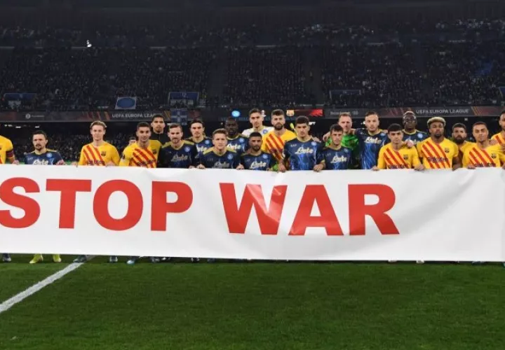 Jugadores del Nápoles y Barcelona sostienen una pancarta que dice "alto a la guerra" antes del partido de vuelta de la eliminatoria de la Liga Europa. Foto:EFE