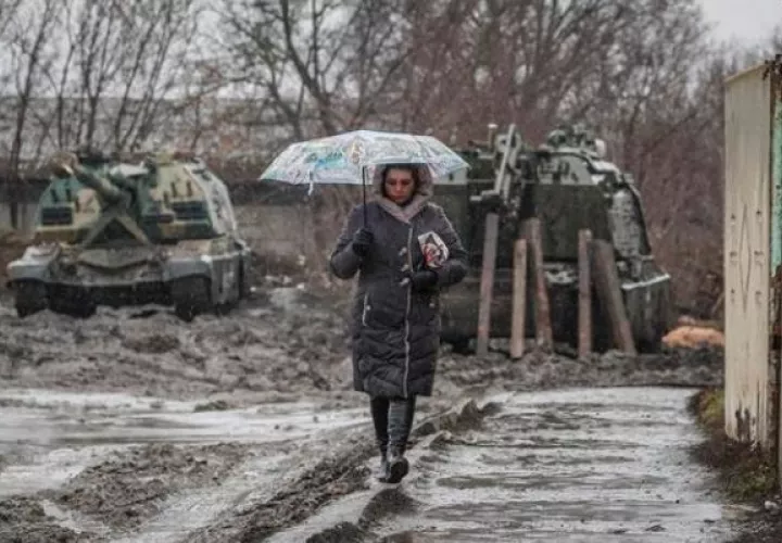 Una mujer camina cerca de vehículos armados en la estación de tren de la región de Rostov, Rusia. EFE