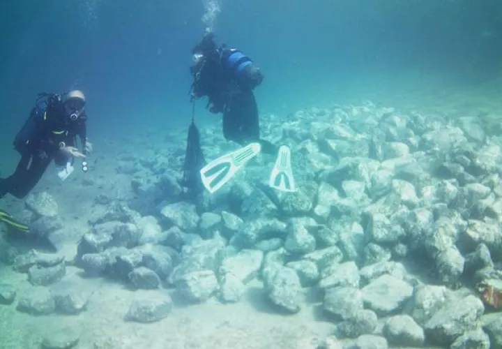 Imagen cedida por el Ministerio griego de Cultura de los arqueólogos examinando rocas en la parte sumergida del asentamiento prehistórico encontrado en Grecia.