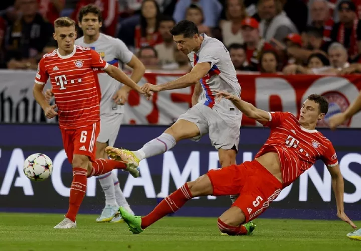  Robert Lewandowski del Barcelona (cent.) patea el balón ante la marca de Benjamin Pavard (der)  y Joshua Kimmich (izq.)  en a Champions. Foto:EFE