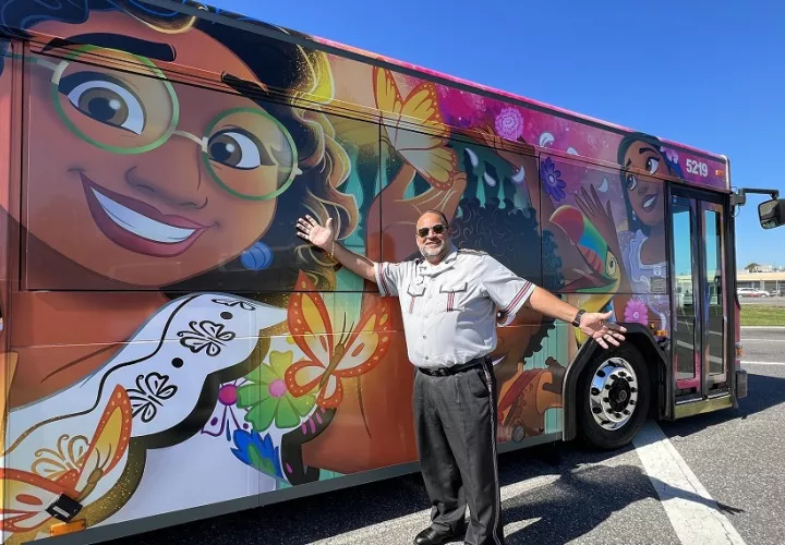 Conductor al lado de un autobús decorado con personajes de la película animada 'Encanto'. Foto: EFE/Disney