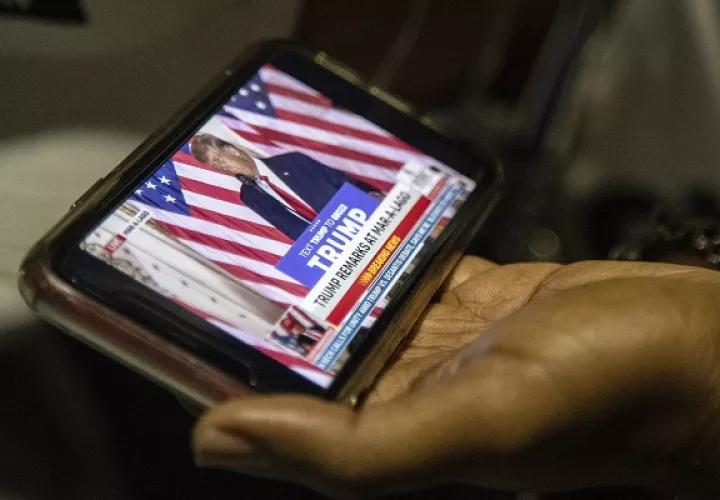 Simpatizantes de Donald Trump siguen su anuncio. Foto: EFE