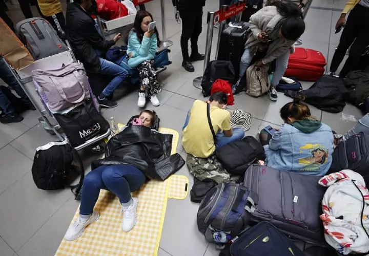 Centenares de personas sentadas en el suelo esperan repuestas. Foto: EFE