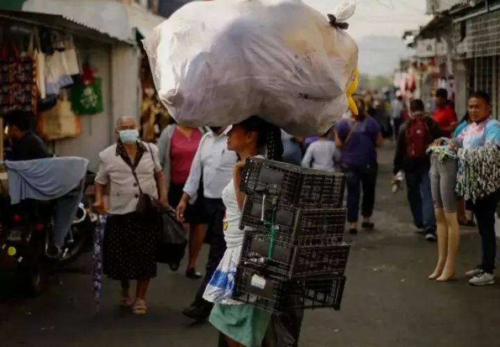 Una vendedora carga su mercadería rumbo a un puesto de venta en un mercado de San Salvador (El Salvador). Foto: EFE