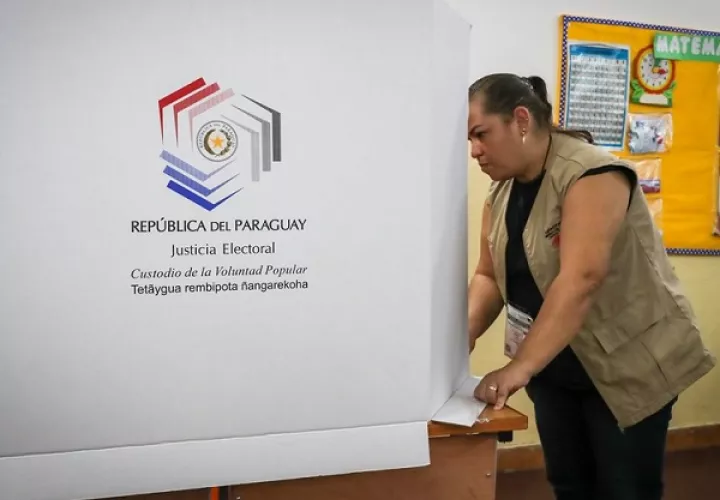 Una funcionaria acomoda una urna en una de las mesas electorales, en Asunción. Foto: EFE