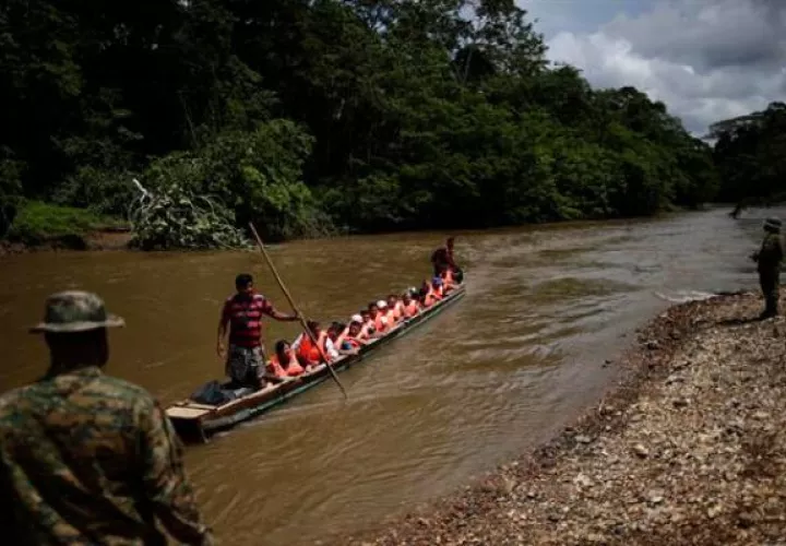 Migrantes son transportados en canoas para ser trasladados a una estación de recepción migratoria. Foto: EFE