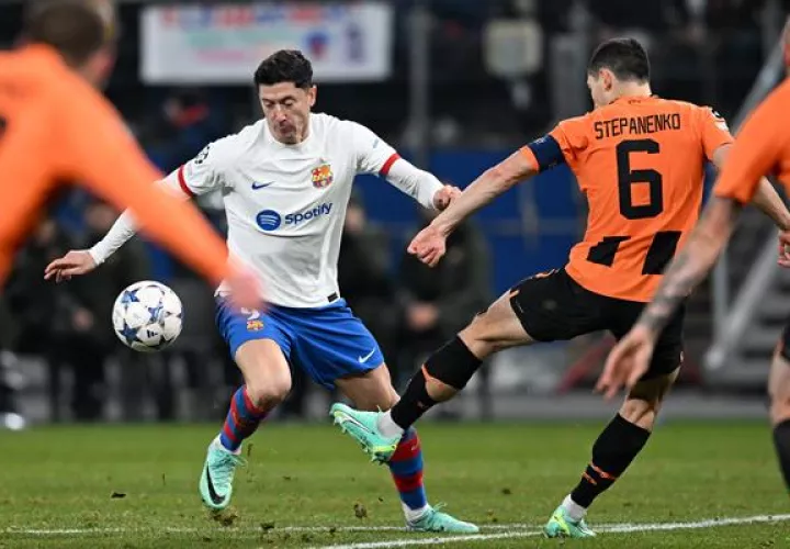 Robert Lewandowski del Barcelona (blanco) en acción contra Taras Stepanenko de Shakhtar Donetsk's (6) en la Champions. EFE