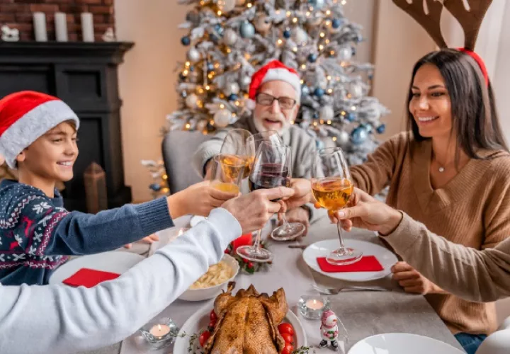 Familia feliz, brindando con vino durante una cena navideña. IMEO