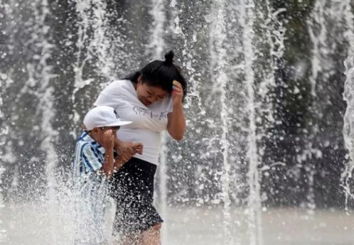 Personas se refrescan en la fuente de la explanada del Monumento a la Revolución en la Ciudad de México. Foto: EFE