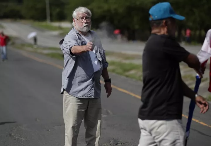 Fotografía del 7 de noviembre de 2023 que muestra a un hombre mientras dispara un arma hacia un manifestante en la vía Panamericana. Foto: EFE/Bienvenido Velasco