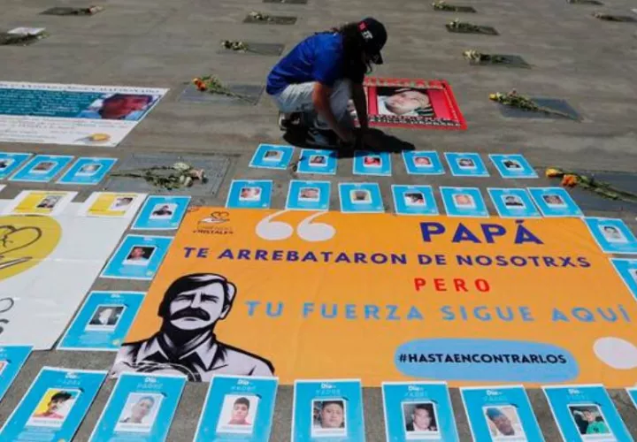 Una mujer coloca flores en memoria de los padres desaparecidos, en la Estela de Luz de la Ciudad de México. Foto: EFE