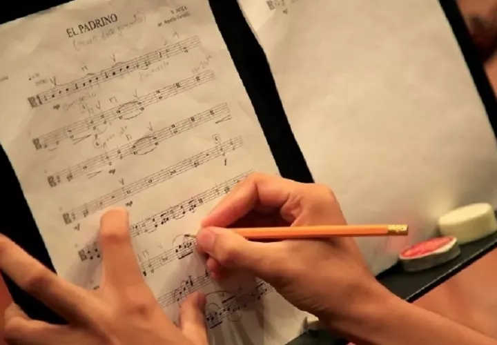 Un integrante de orquesta escribe sobre una partitura.  Foto: EFE / Ricardo Maldonado