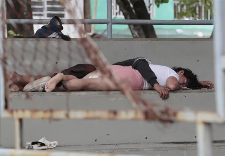Migrantes duermen en las gradas de un coliseo.