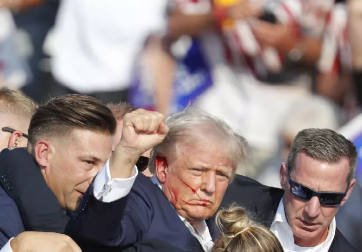 Donald Trump caminó con el puño en alto desde el escenario rodeado de los elementos del Servicio Secreto, pero las imágenes dan a entender que fue herido. Foto. EFE
