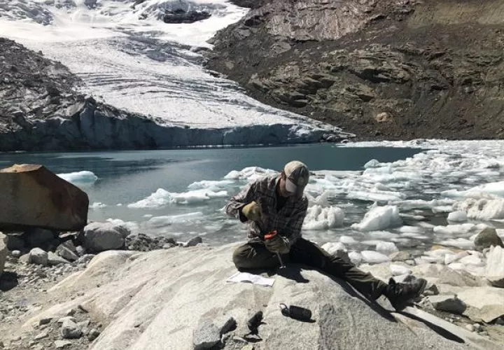 Un investigador recoge una muestra de lecho rocoso del glaciar Queshque, en los Andes peruanos. Foto: EFE