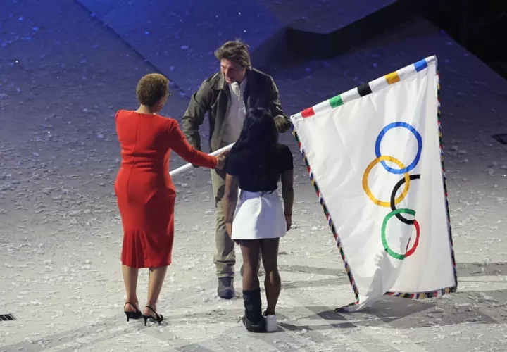 La alcaldesa de Los Angeles, Karen Bass (i), y la gimnasta Simone Biles, entregan la bandera olímpica actor estadounidense Tom Cruise. Foto: EFE