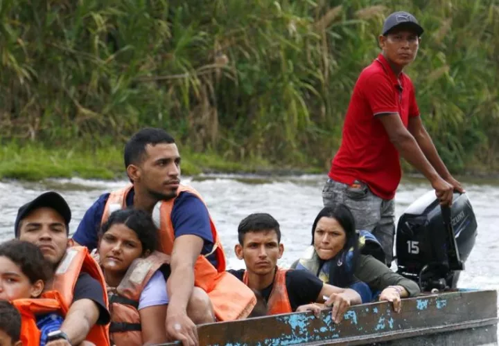 Migrantes se transportan en una lancha por el río Turquesa. Foto: EFE