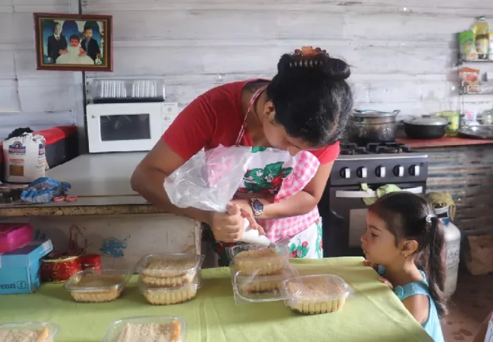 Mientras Orieli Figueroa mientras realiza sus labores de repostería supervisa la tarea de su hija. Foto. Mides