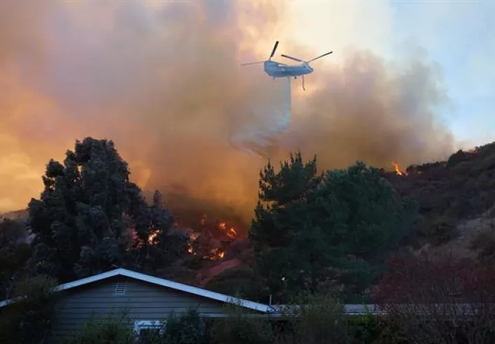 Un helicóptero arroja agua sobre una casa durante el incendio forestal de Palisades en Los Ángeles, California (EE.UU.). EFE