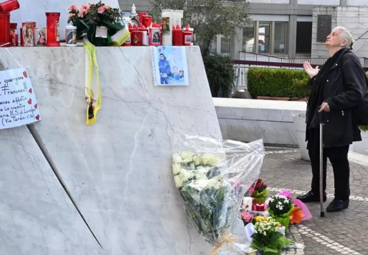 Una mujer reza bajo una estatua del Papa San Juan Pablo II en las afueras del Hospital Universitario Gemelli. Foto: EFE