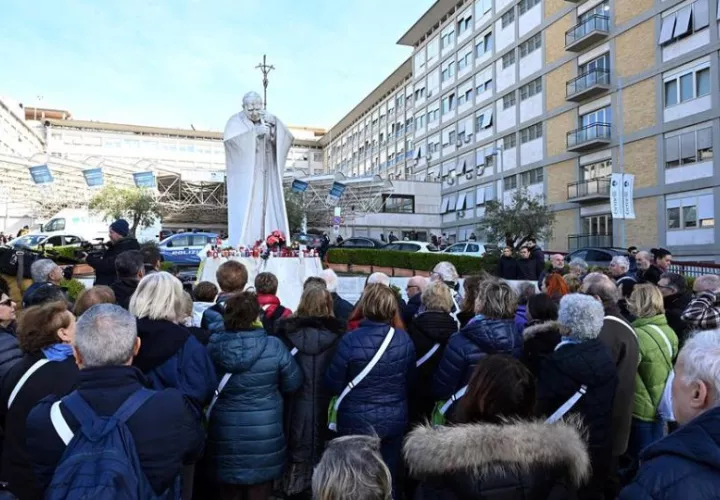 Fieles rezan por el papa Francisco ante la estatua del Papa San Juan Pablo II. Foto: EFE